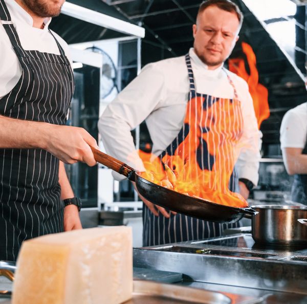 Restaurant kitchen workers beside an open flame