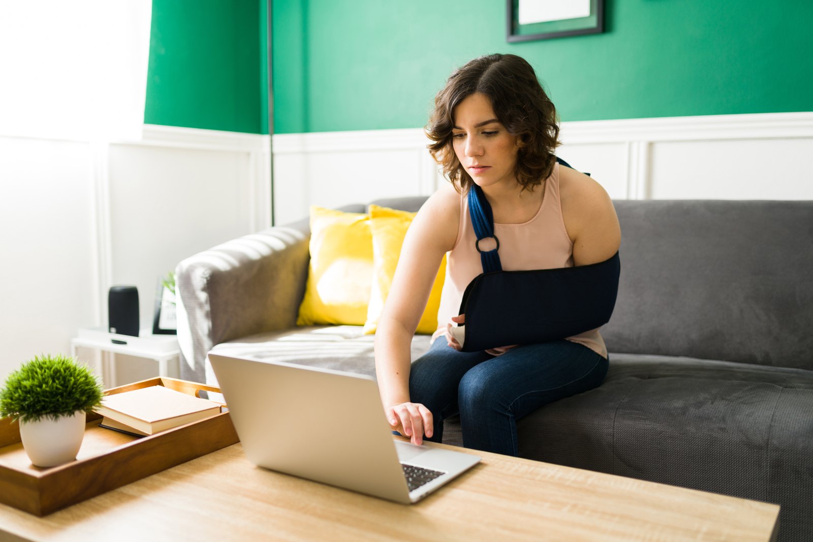 Woman with an arm in a sling using a laptop at home