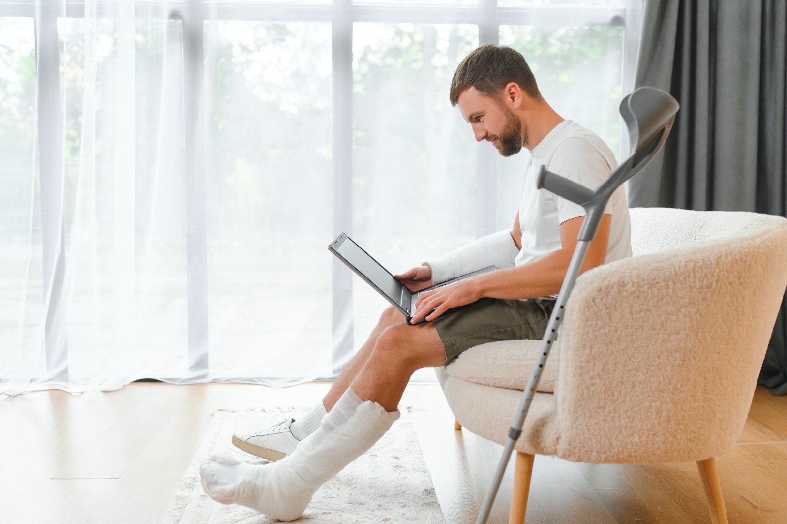 Man with an injured leg using a laptop at home