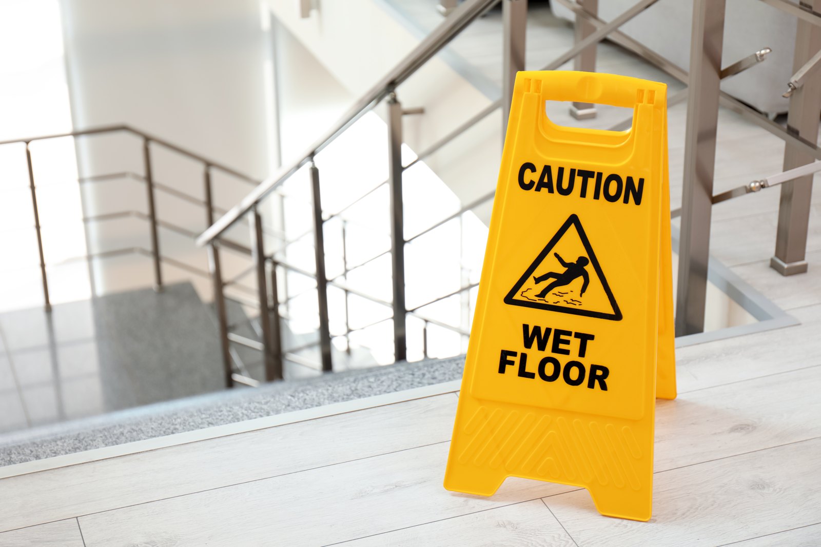 Wet-floor warning sign beside an indoor staircase
