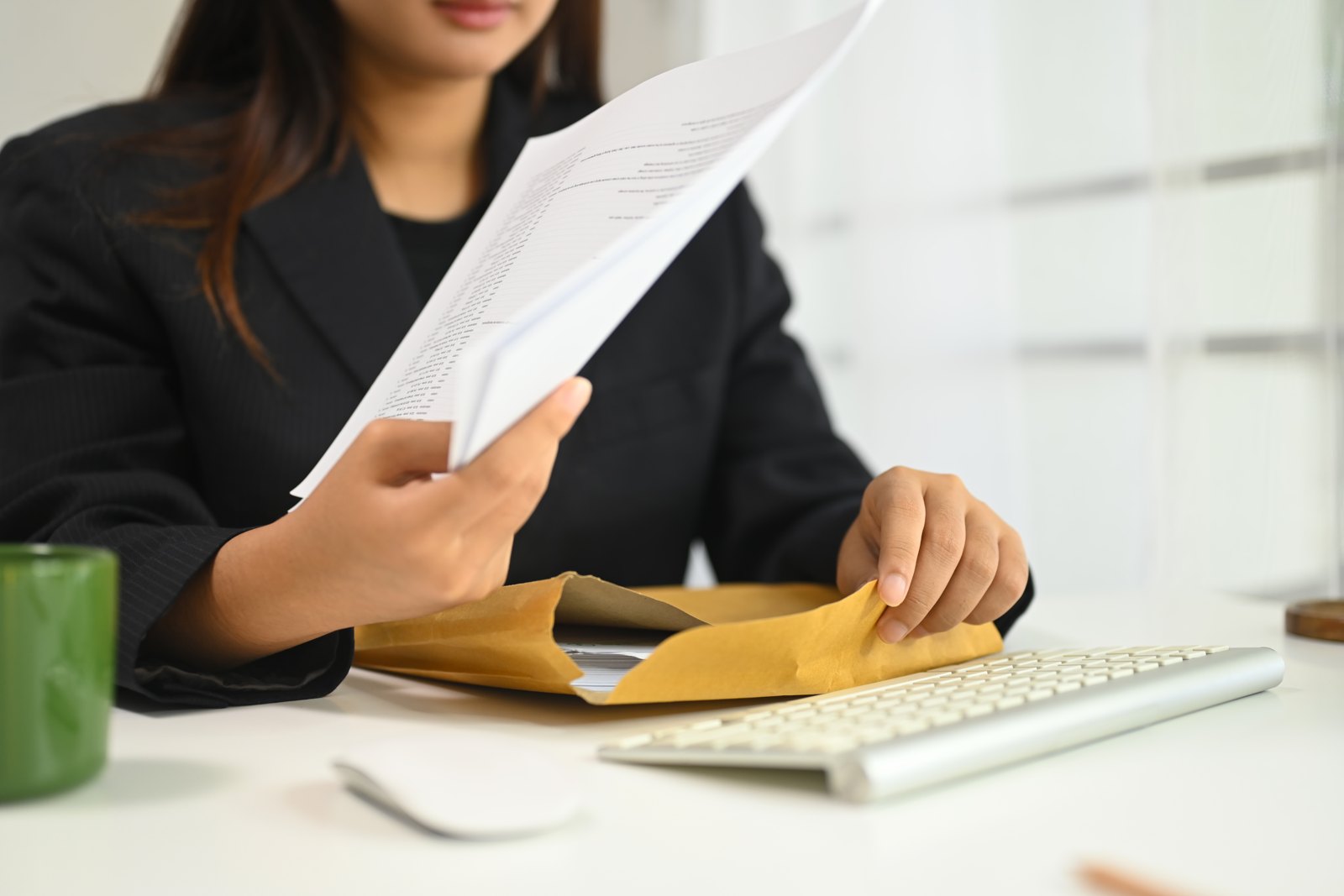 Woman reviewing documents and an envelope at her desk